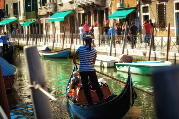 Gondolier with tourists guiding his boat through the canals of Venice
