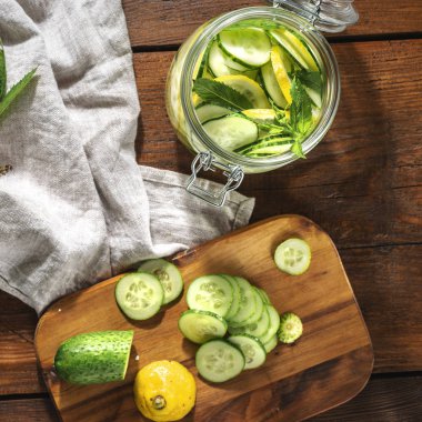 Salatalıklı detoks suyu ve ahşap masa manzaralı cam kavanozda limon.