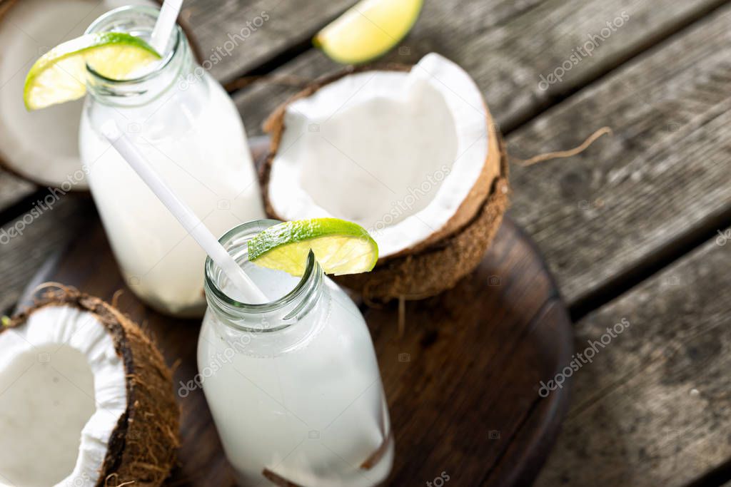 Coconut water in bottles on wooden table. Healthy drinks concept