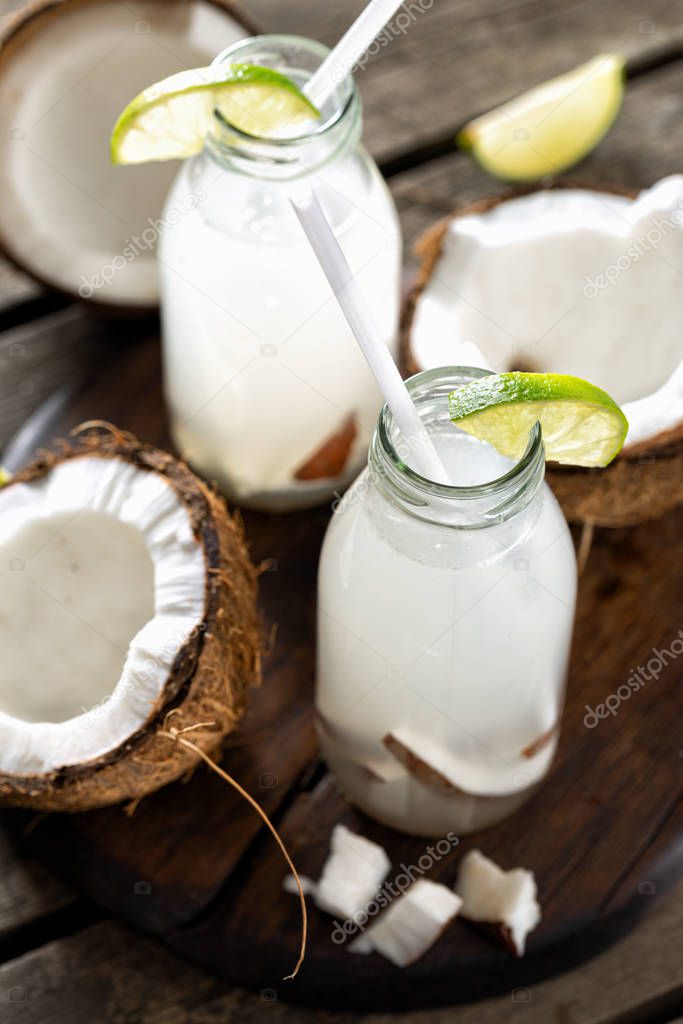 Coconut with coconut water in bottles on wooden table. Healthy drinks concept