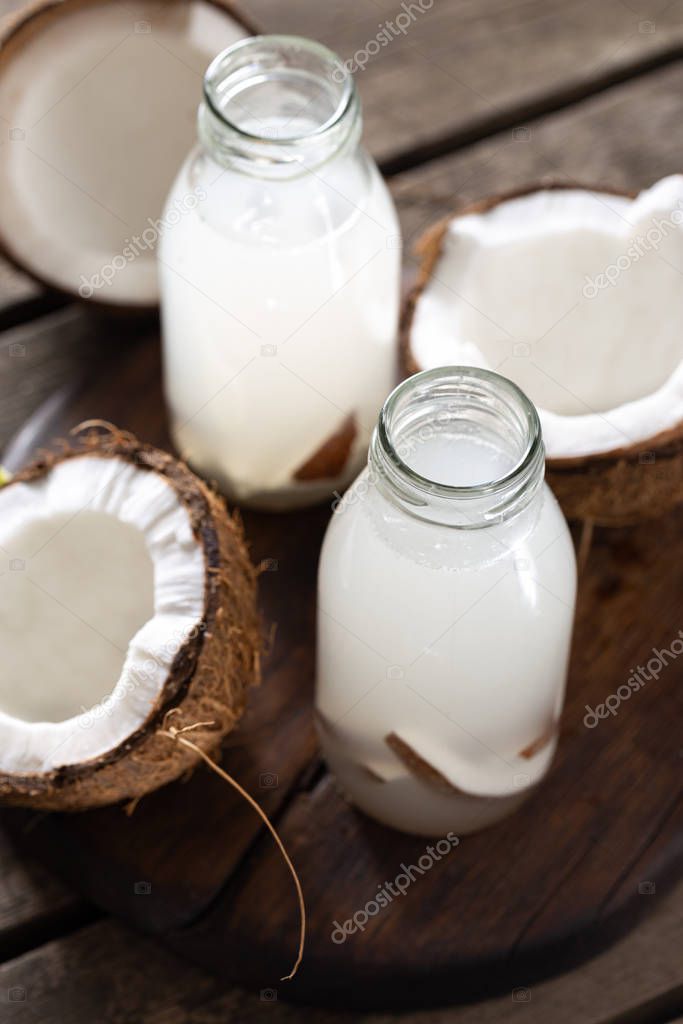 Fresh coconut water in bottles on wooden table