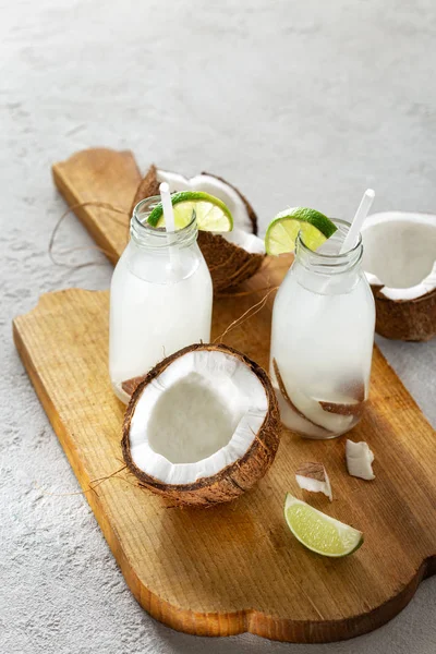 Coconut with coconut water in bottles on light background. Healthy drinks concept