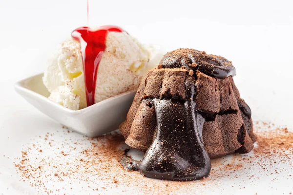 Melted chocolate cake on white plate with ice cream and raspberry or strawberry jam close up