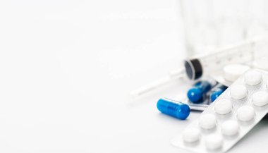 Çeşitli ilaç hapları, kapsüller, tabletler ve şırıngalar beyaz arka planda fotokopi alanı ile