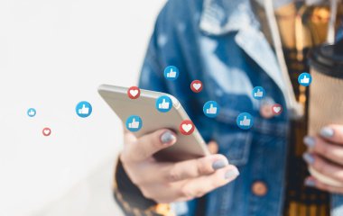 Sosyal medyayı akıllı telefonlarında kullanan genç bir kadın sokakta yürüyor.