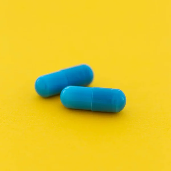 Lek Farmaceutyczny Niebieska Kapsułka Tabletki Żółtym Tle — Zdjęcie stockowe