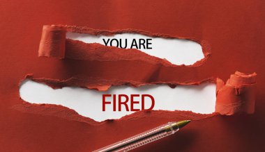 Red torn paper with inscription you are fired and pen close up clipart