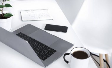 Bilgisayarlı ev ofisi, not defteri, bir fincan kahve ve akıllı telefon. Uzak çalışma veya çevrimiçi öğrenme kavramı 