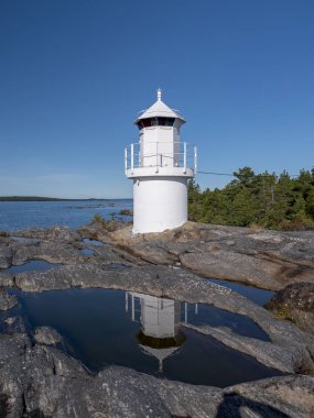 Kayalık sahilde bulutsuz gökyüzüne, Hlik 'te deniz fenerine bakan beyaz bir deniz feneri.