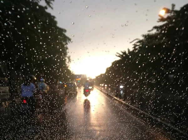 Blurred raindrops with street view on car wind shield in the eve — Stock Photo, Image