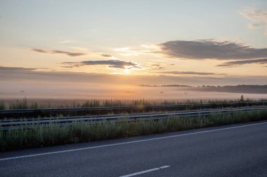 Arazide ve yolda sisli altın gün doğumu.