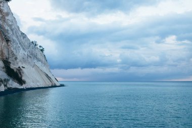 Güneşin doğuşunda denizde ağaçlı bir kaya.