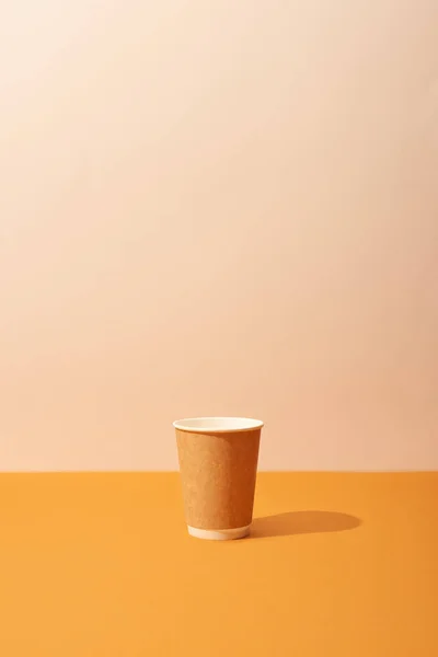 clear cup off coffee on orange table in front of the brown wall