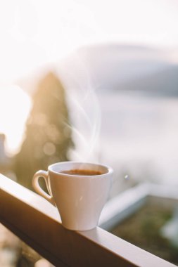 İsviçre Alplerinde gün doğumunda balkonda bir fincan kahve.