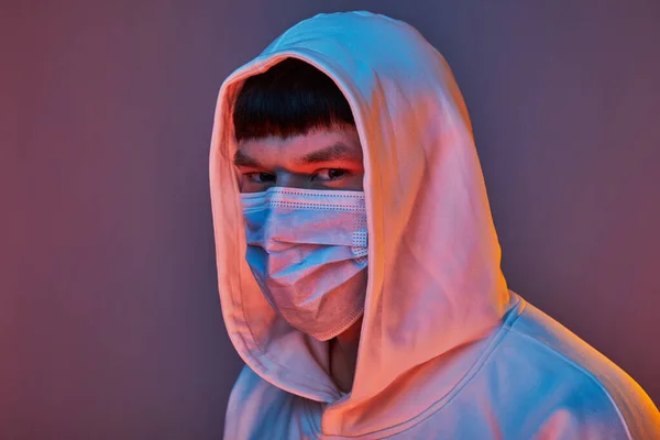 close-up of a man in a medical mask and white clothes on a colored background