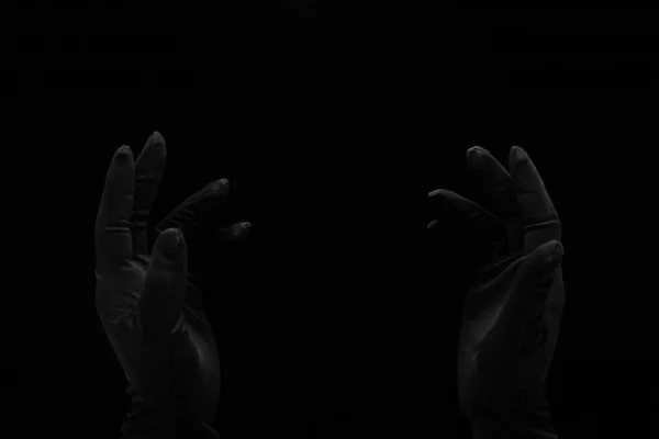 空空的手戴着黑色手套在黑色的背景上伸向空虚 — 图库照片