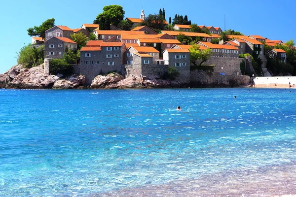 Montenegro's a major tourist attraction - the island of Sveti Stefan, the blue crystal clear sea, people swim — Stock Photo, Image