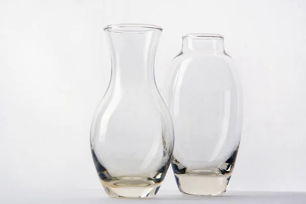 Dois vasos de vidro de formas diferentes estão lado a lado em um fundo branco — Fotografia de Stock