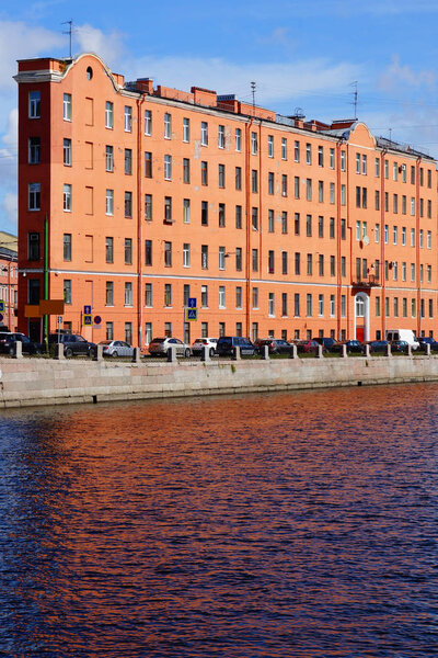 Narrow terracotta building on the waterfront of the river.