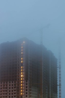 Sitesi, bitmemiş evleri inşaat vinç, alacakaranlık, zemin aydınlatma akşam üst katlarda sis kapsar