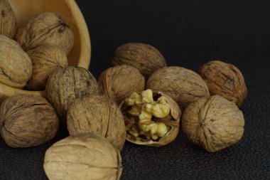 Ceviz bambu kaseden siyah bir arka plan üzerine dökülür. Sağlıklı yeme, iyi beyin için.