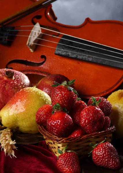 Violin and strawberries in a basket, wet and juicy
