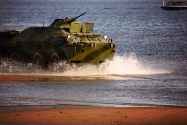 A military tank rides the water at sea, scattering water splashes clipart