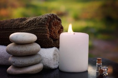 Spa havlu, yanan muma, banyo yağı ile hayat hala ve taş yeşil bir bahçe zemin karşı Masaj