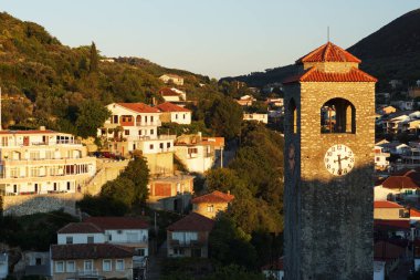 Şafak küçük bir kasabada, güneş kırmızı kiremitli çatılı taş bir kilise aydınlatır.