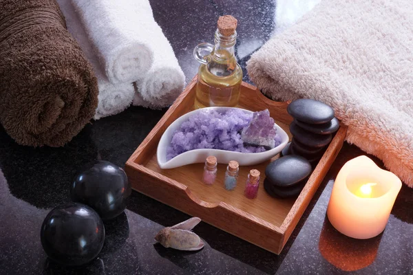 Bir kaplıca tedavisi mor tuz, sıcak aromatik yağ ve yumuşak havlu ile ayarla. Masaj yalan kümesinin yanındaki siyah Bian taşları.