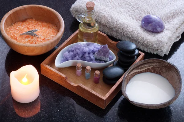 En kokosnötskal med mjölk tillsammans med en spa-behandling set med orange badsalt, lila massage salt, varma stenar, aromatisk olja och mjuka handdukar. — Stockfoto