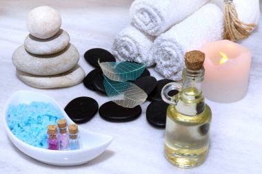 Spa yordamı için hazırlık bir beyaz mermer masada, işte bir aromatik yağ, taşlar ve Masaj, rulo yumuşak havlular ve güvenli bir elektrikli mum için tuz.