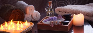 Elektrik yanan mumlar ve terry havlu ile spa uygulamaları için ayarlayın. Bir ahşap kutu yağ ve Masaj, tuz ve ametist mor, çok renkli tuz kavanoz bir dizi için taş.