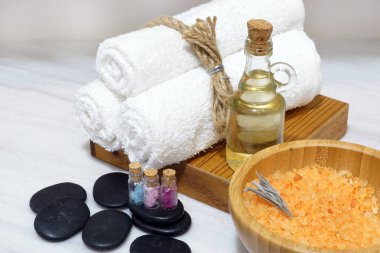 Spa yordamlar için bir küme bir aromatik yağ, yumuşak havlu, sıcak taşlar ve banyo tuzu kaşıkla ahşap bir kasede makyaj