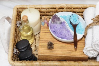 Bir hasır sepet Spa yordamlar, renkli bir tuz, aromatik yağ, taşlar, bir mum ve yumuşak havlular için bir kümesiyle bir parçası