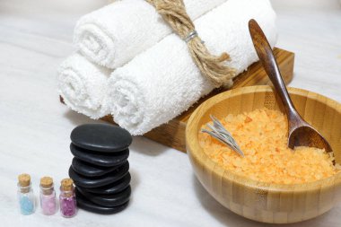 Kabarcıkları ile çok renkli tuz, yumuşak havlular, sıcak taşlar ve banyo Spa yordamlar için bir küme bir kaşık makyaj ile ahşap bir kase içinde tuz