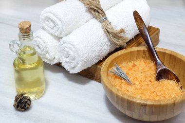Spa prosedürü - turuncu banyo tuzu bir ahşap kase ve kaşık, üç beyaz havlu bir ahşap kutu ve aromatik yağı masaj bir beyaz mermer tablo için bir şişe için hazırlık