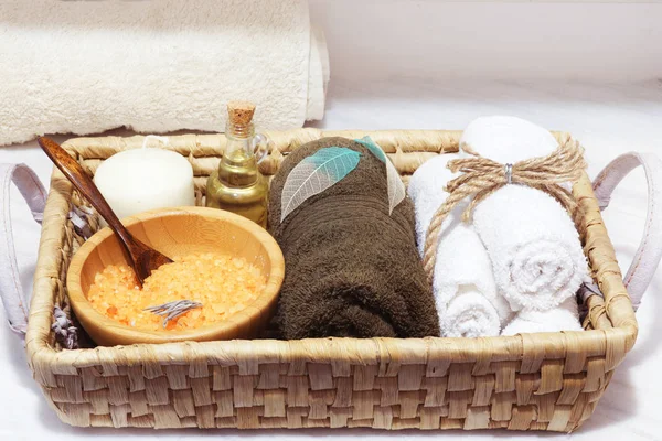 Cesta de vime com conjunto de tratamento de spa, sal marinho, óleo aromático, pedras, vela e toalhas macias decoradas com folhas esqueletizadas — Fotografia de Stock