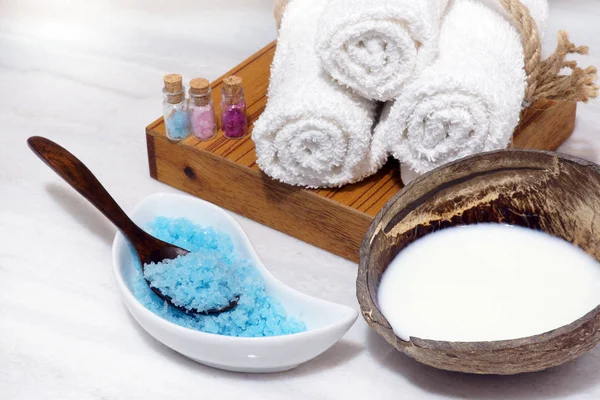 Spa yordamlar için Hindistan cevizi yağı, yumuşak havlu ve mavi banyo tuzu beyaz mermer masaya ayarla.