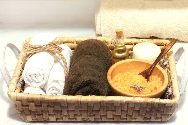 Panier en osier avec un ensemble de soins spa, sel de mer, huile d'arôme, pierres, bougie et serviettes douces — Photo