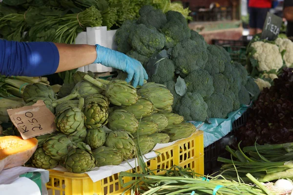 Lateks eldiven satıcı enginar brokoli İspanya sebze pazarında yanında sayaç alır