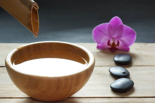 Instellen voor spa procedures, stenen voor hete massage en op smaak gebrachte water, gerekruteerd uit een bamboe-stam in een kom — Stockfoto