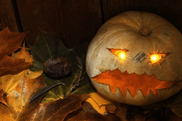 Хэллоуин Джек-Фонарь с осенними листьями рядом с деревянным фоном — стоковое фото