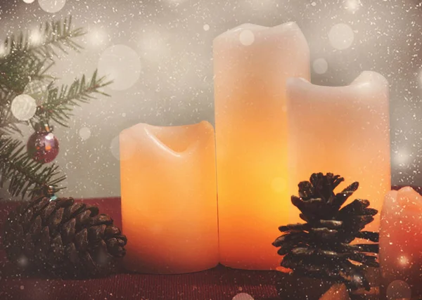 Brennende Kerzen stehen neben einem Weihnachtsbaum und Zapfen — Stockfoto