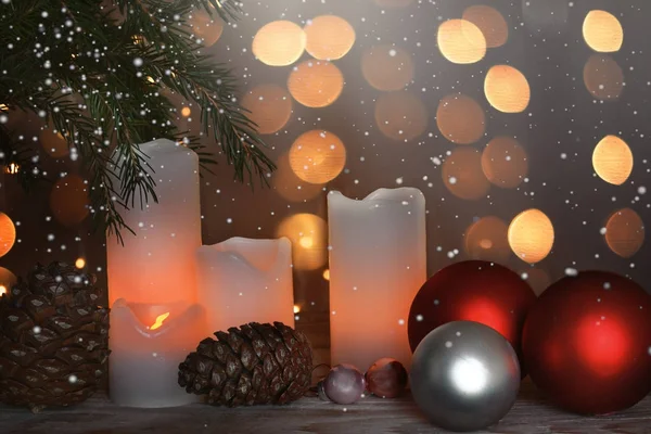 Stillleben mit brennenden Kerzen, Zapfen und festlichen Kugeln neben einem Weihnachtsbaum und Girlanden im Hintergrund — Stockfoto