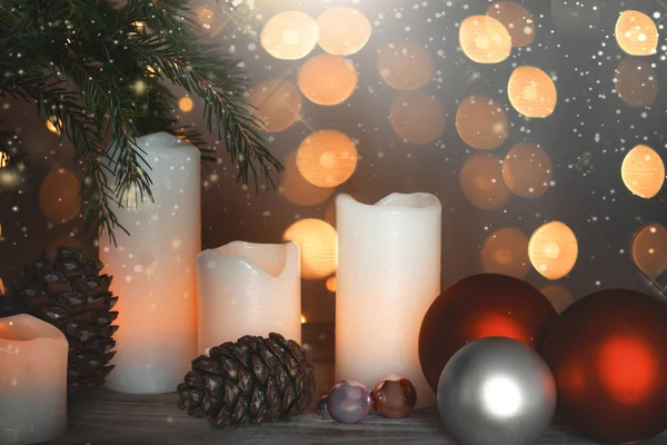 Nature morte du Nouvel An avec des bougies allumées, des cônes et des boules festives à côté du sapin de Noël et des guirlandes en arrière-plan . — Photo