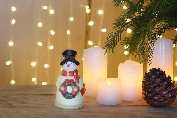 Weihnachtskarte mit festlichem Kranz, ein Schneemann steht auf einem Holztisch — Stockfoto