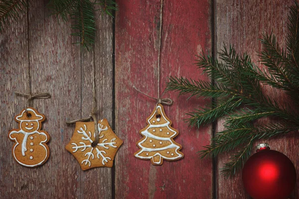 Os biscoitos suspendem-se em cordas de uma parede de madeira, ramo de abeto com a bola festiva — Fotografia de Stock