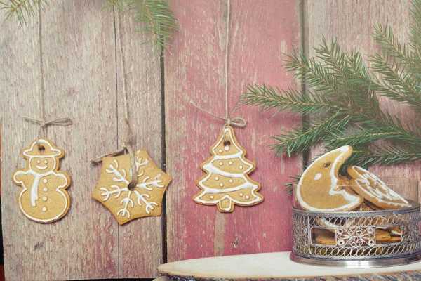 Las galletas cuelgan de las cuerdas de una pared de madera, cerca de un jarrón con galletas de Navidad — Foto de Stock