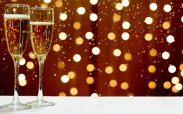 Dois copos de champanhe espumante no fundo de guirlandas festivas, neve branca cai — Fotografia de Stock